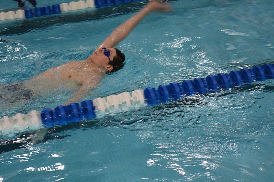 Freshman Logan Steckleberg swimming backstroke