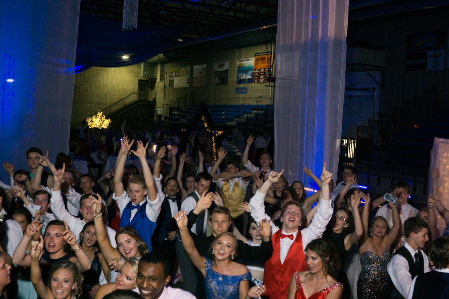 Prom goers throw their hands in the air at the dance
