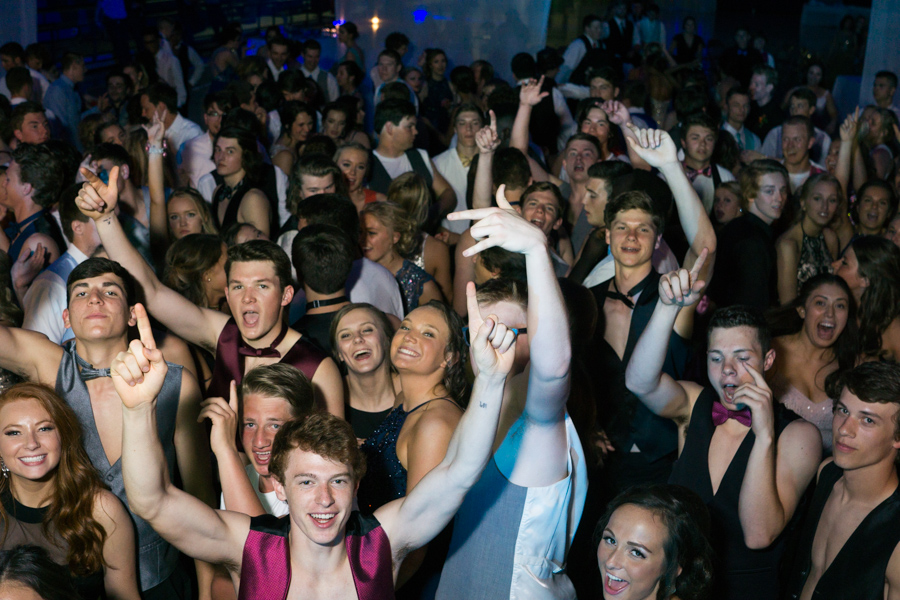 Prom goers throw their hands in the air for the camera