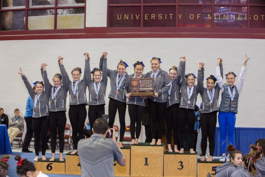 The OHS Gymnastics team on the podium after receiving medals and the trophy