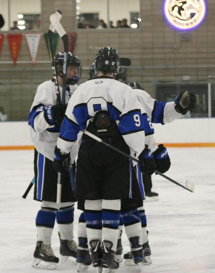 A group of teammates talks on the ice 