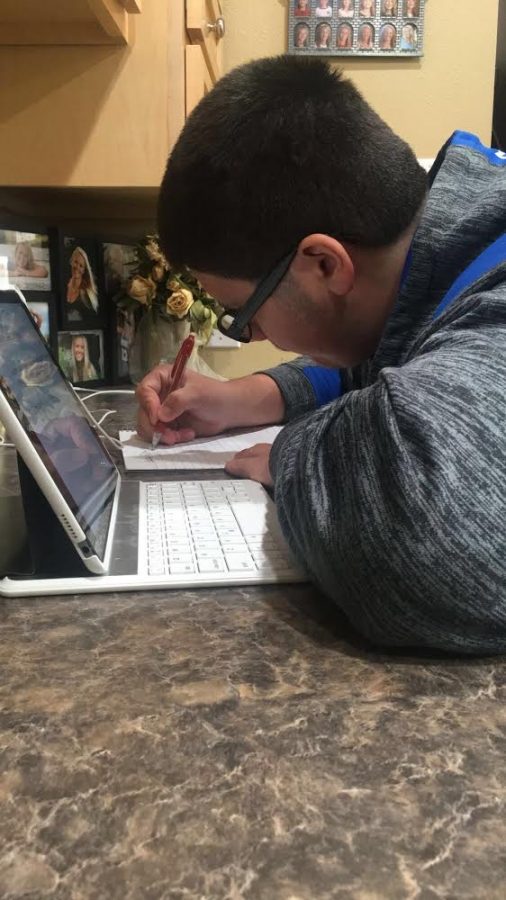Sophomore Izaya Vazquez participates in distance learning by completing his homework on a computer