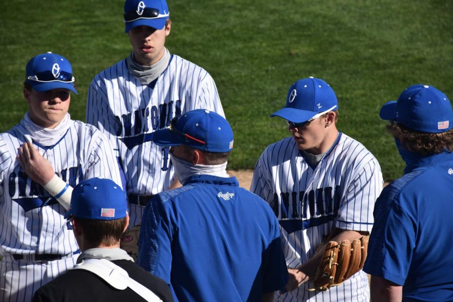 The Owatonna Baseball team meets outside of the dugout after a tough inning in the field.
