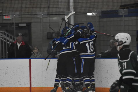 The boys hockey team celebrates a goal with a huddle in the corner against the Faribault Falcons.