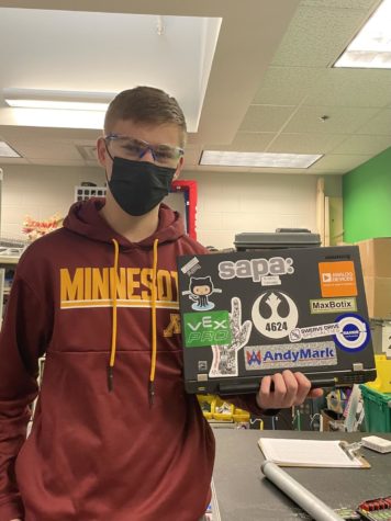 Junior Aiden Engel displays the Robotics teams ThinkPad laptop, which is covered in stickers that represent the team.