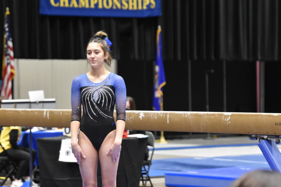 Sophmore Emma Johnson smiling at the judge moments before preforming her beam routine.