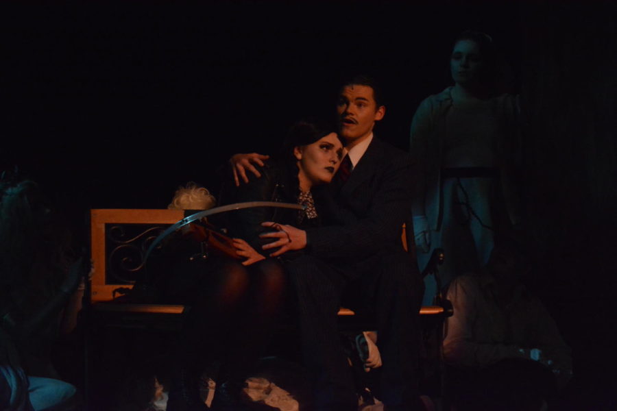 Wednesday (Ava Eitrheim) and Gomez Addams (Jackson Hemann) sitting together on a park bench.