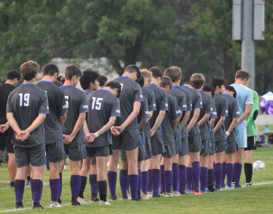 Owatonna Boys Soccer team stands for minute of silence for former teammate.