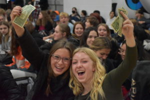 Seniors Ella Hayes and Emma Myer hold up money at the kickoff pep fest.
