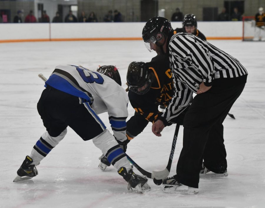 PUCK DROP. Senior Ezra Oien waiting at the face-off as the ref drops the puck.