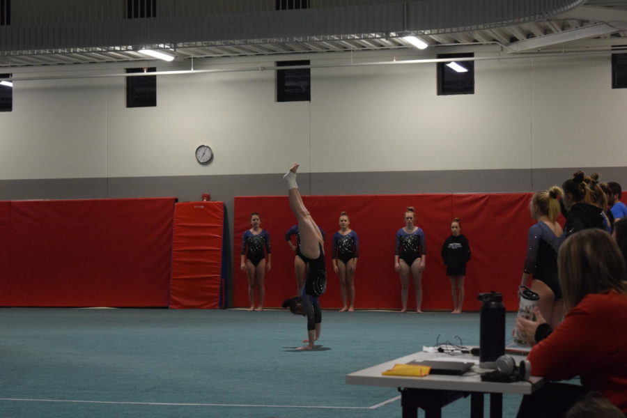 Kaitlyn Cobban, senior, in a handstand while tumbling during a meet on December 15, 2022.