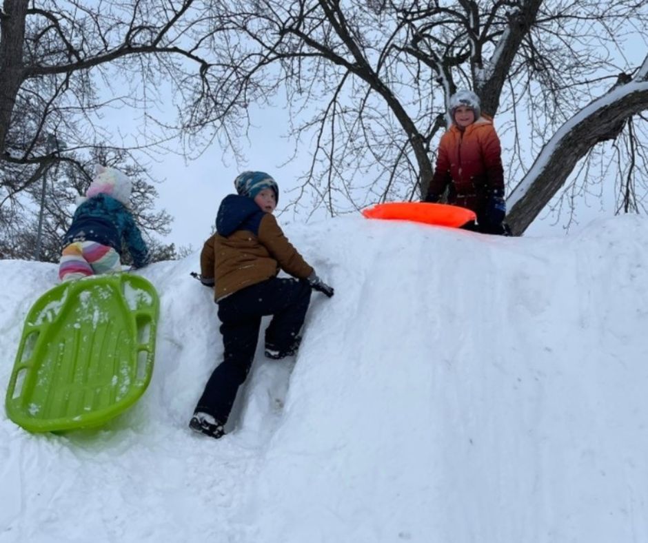 Owatonna Students sledding down a snow hill in Lincion School 