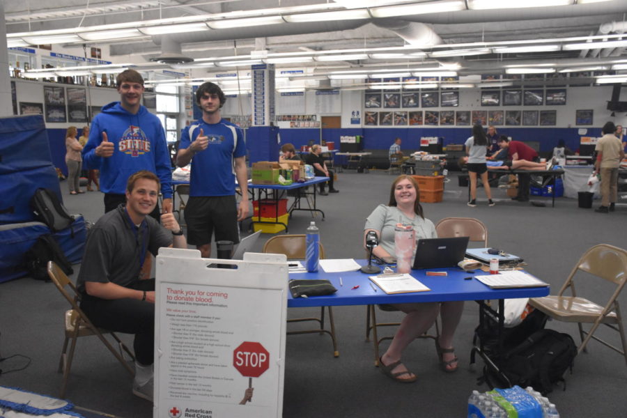 Adviser Jacob Kringen posing for a picture with three NHS members ready to sign people in to donate blood. 