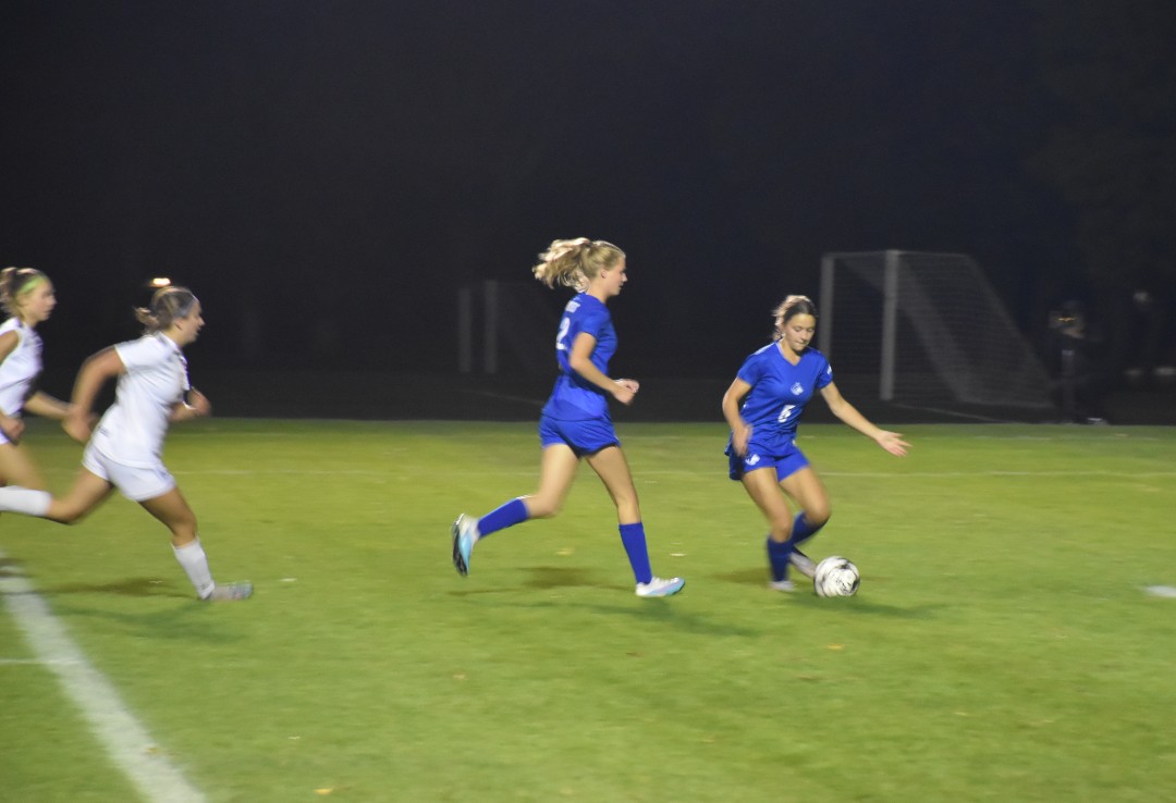 Izzy Muir controls the ball while the opposing team pressures her.