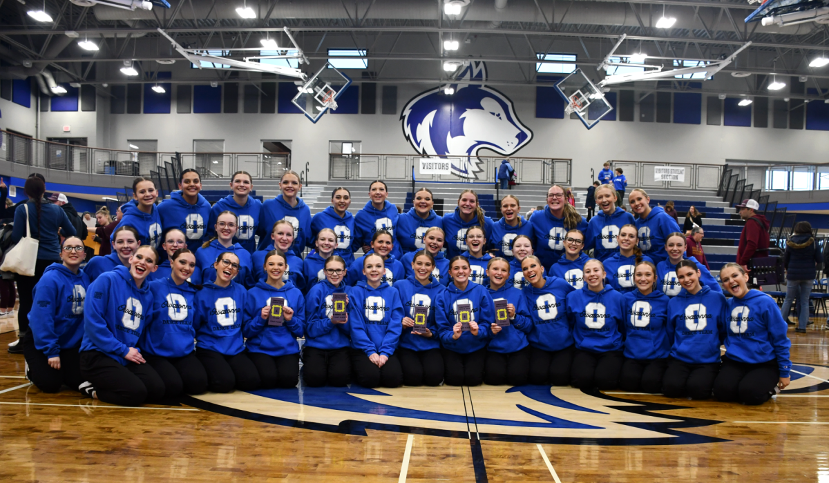 The dance team smiling for the camera with their awards after their successful home competition. 