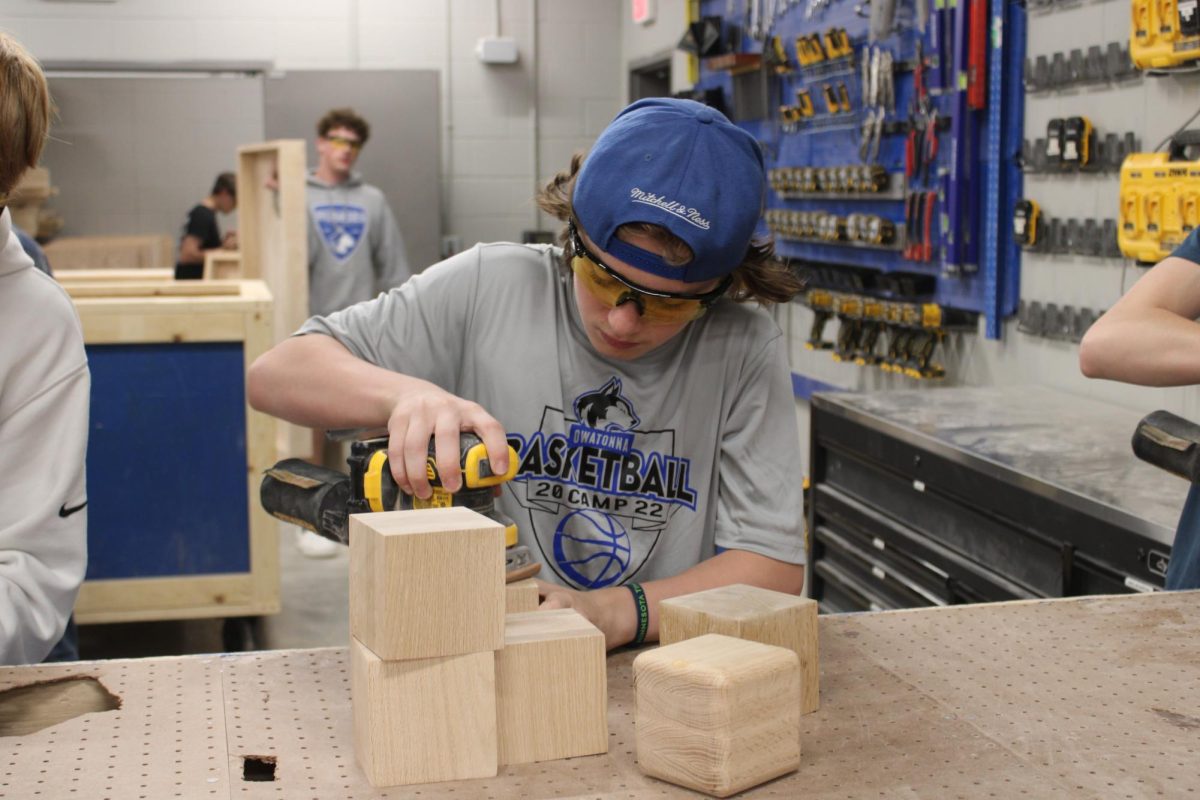 Freshmen Brennan Aus sands his final project for Woods I.