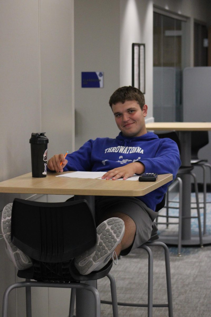 Junior Eli Black smiles at the camera instead of working on his math homework.