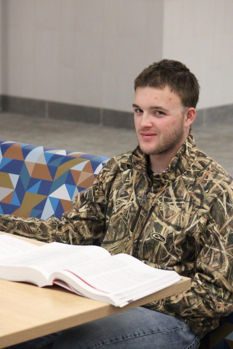 Jay quaintance smiles at the camera while he works on his assignments. 