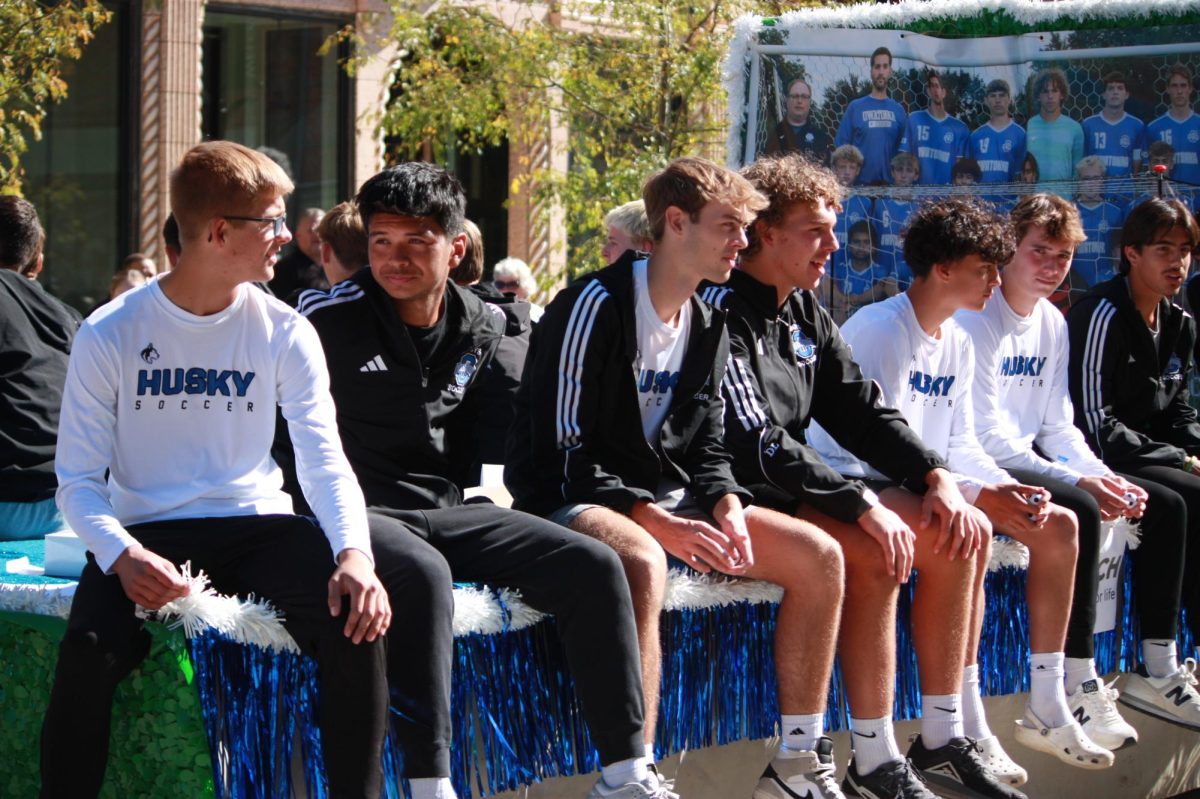 Owatonna Boys Soccer team sits and throw mini soccer balls to audience.  