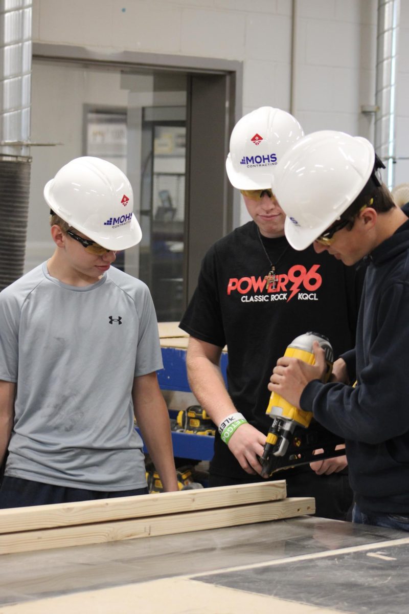 Three OHS construction students put the donated hard hats to use in the classroom.