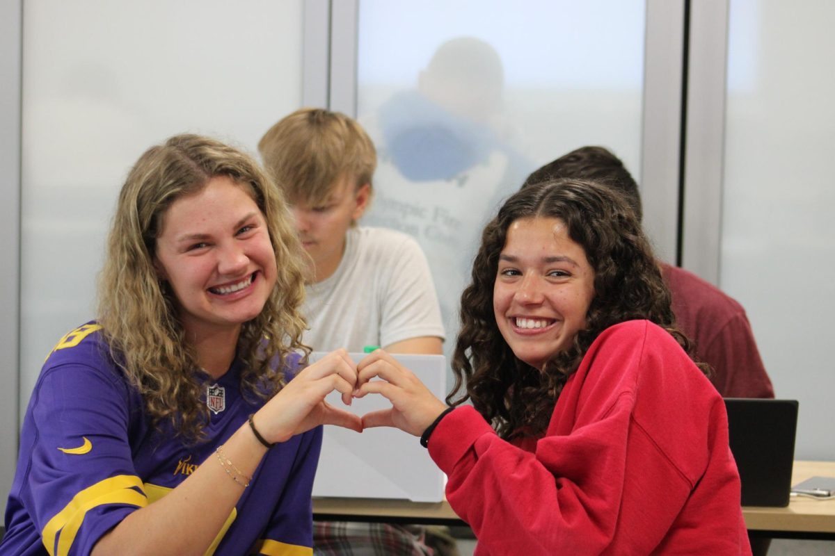 Seniors Lexie Klecker and Preslee Hodgman putting up a heart sign.