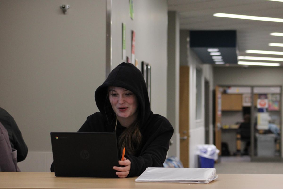 Senior Jordan Otte is glancing at her chromebook while doing homework.