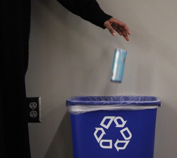 A student throws their drink into the recycling bin. 