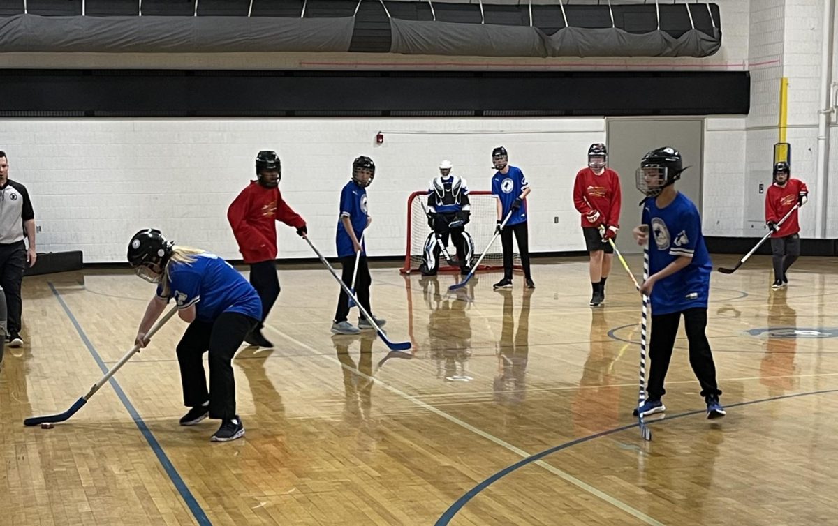 OHS Adaptive Floor Hockey members attack the puck in attempts to make a goal.