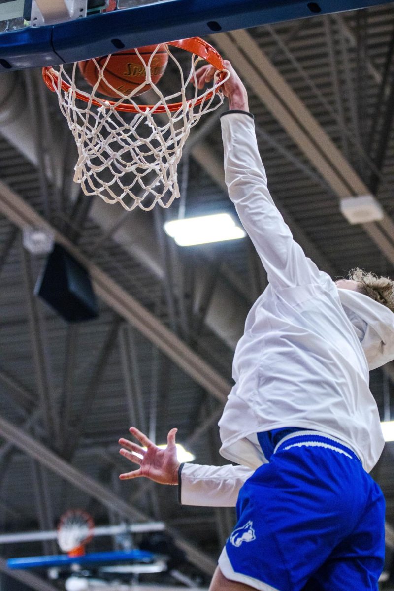 Freshman Cooper Routh dunks the basketball in warmups in the varsity game.