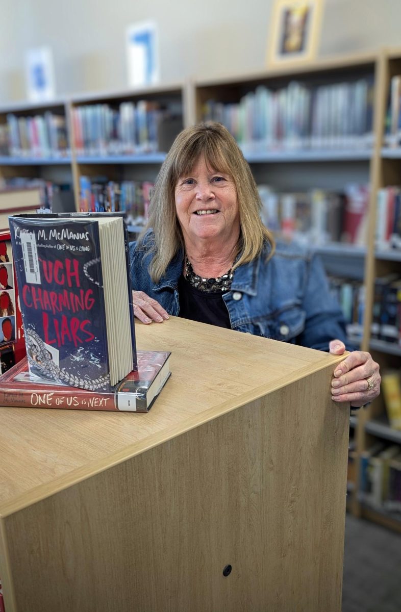 Ms. Diane Watts stands behind one of the bookshelves in the library section. She enjoys adjusting to challenges with book censorship.
