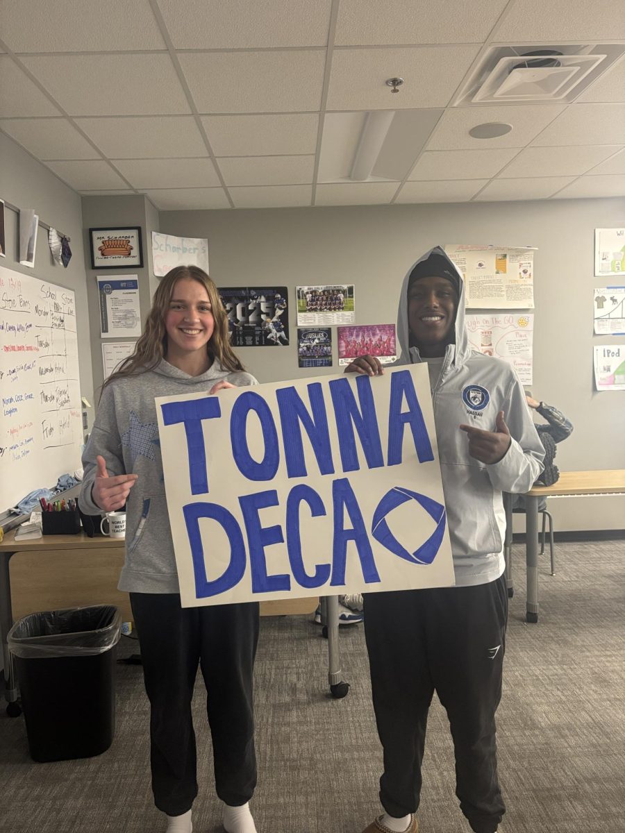Junior Audrey Dowling (left) and Senior Mubarak Hassan (right) posing with homemade Owatonna DECA poster.