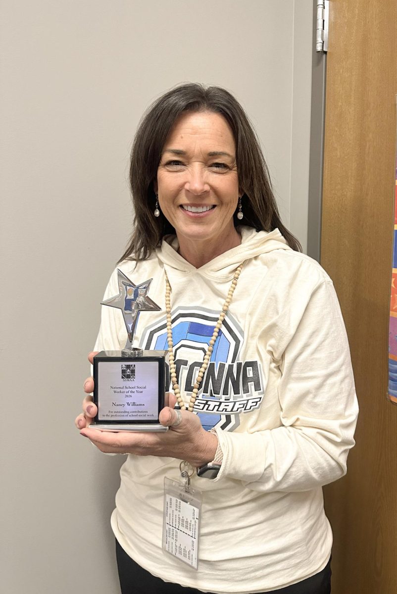 Nancy Williams standing in her office holding her trophy stating “National School Social Worker of the Year 2026 Nancy Williams. For outstanding contribution to the profession of school social work.” 